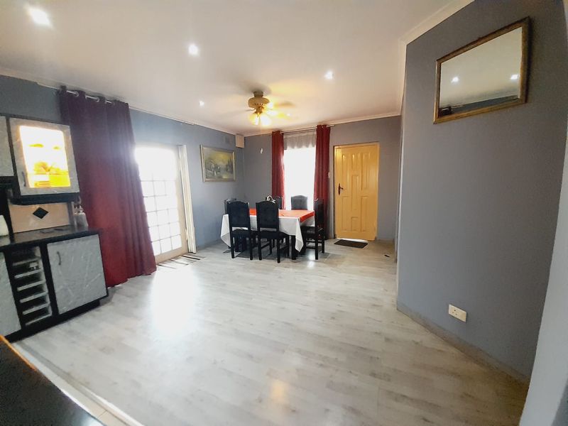 Open plan living and dining area featuring laminate flooring, recessed downlighting, a ceiling fan, and direct access to the exterior via a glass panel door.