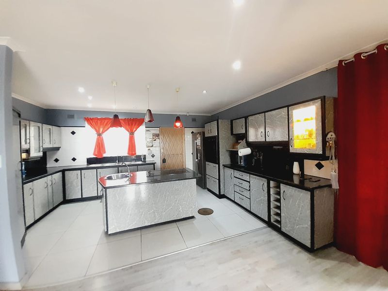Spacious kitchen featuring a central island, extensive built-in cabinetry, stone countertops, and tiled flooring with recessed lighting throughout.