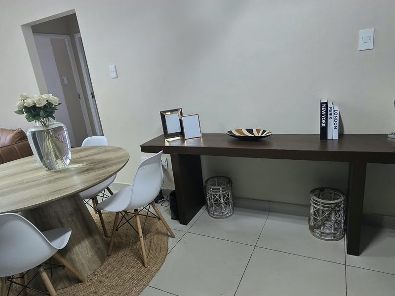 A well-maintained living area featuring neutral tiled flooring and clean wall finishes, providing a versatile space for dining or relaxation.
