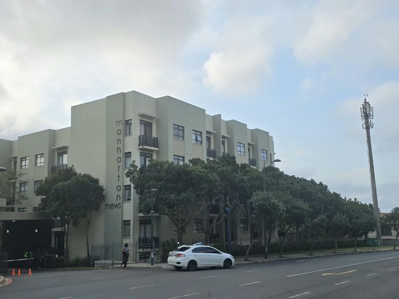 Exterior view of the Manhattan Mews apartment complex, featuring a multi-story building with balconies and secure street-level access.