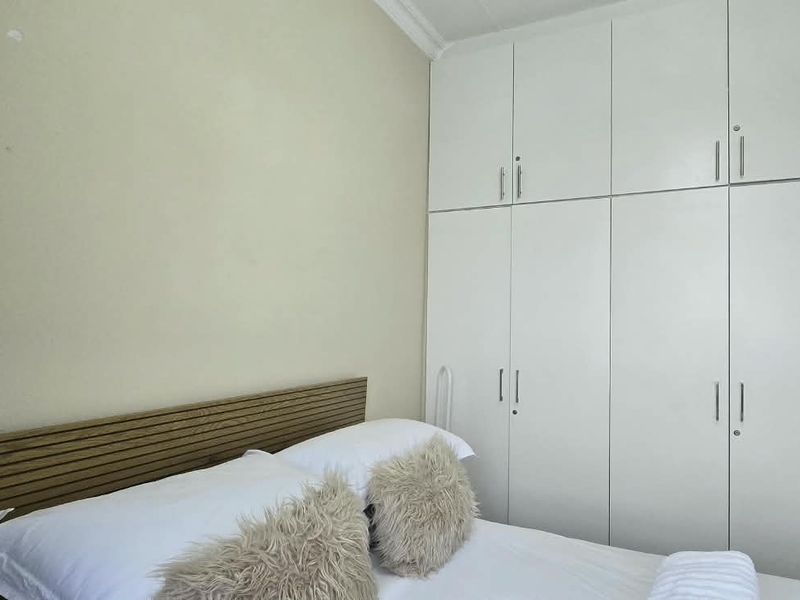 A bedroom featuring floor-to-ceiling built-in cupboards and decorative cornice detailing.