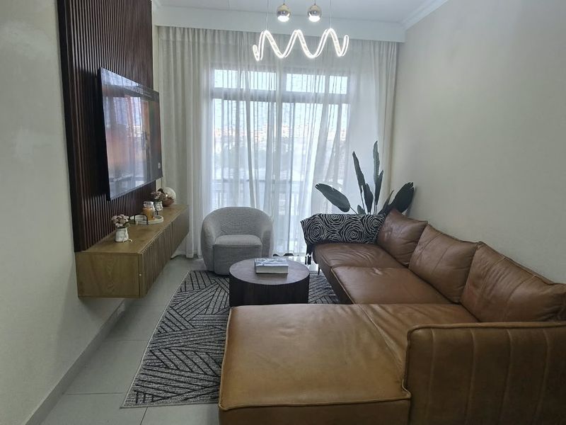 A modern living room featuring a stylish slatted wood accent wall, floating media console, tiled floors, and large windows with floor-to-ceiling curtains.