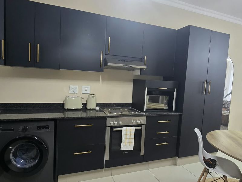 Modern open-plan kitchen featuring dark cabinetry, granite countertops, integrated appliances, and a seamless flow into the adjacent living and dining area.