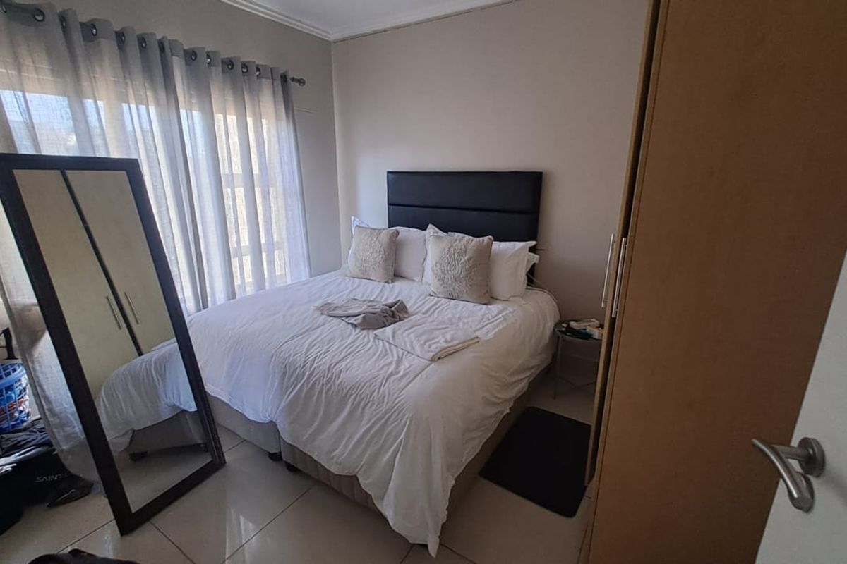A functional bedroom featuring tiled flooring, a built-in wardrobe, and large windows with curtain rails, providing a neutral base for personalization.