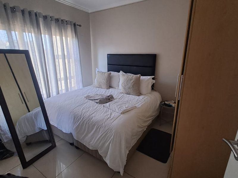 A functional bedroom featuring tiled flooring, a built-in wardrobe, and large windows with curtain rails, providing a neutral base for personalization.