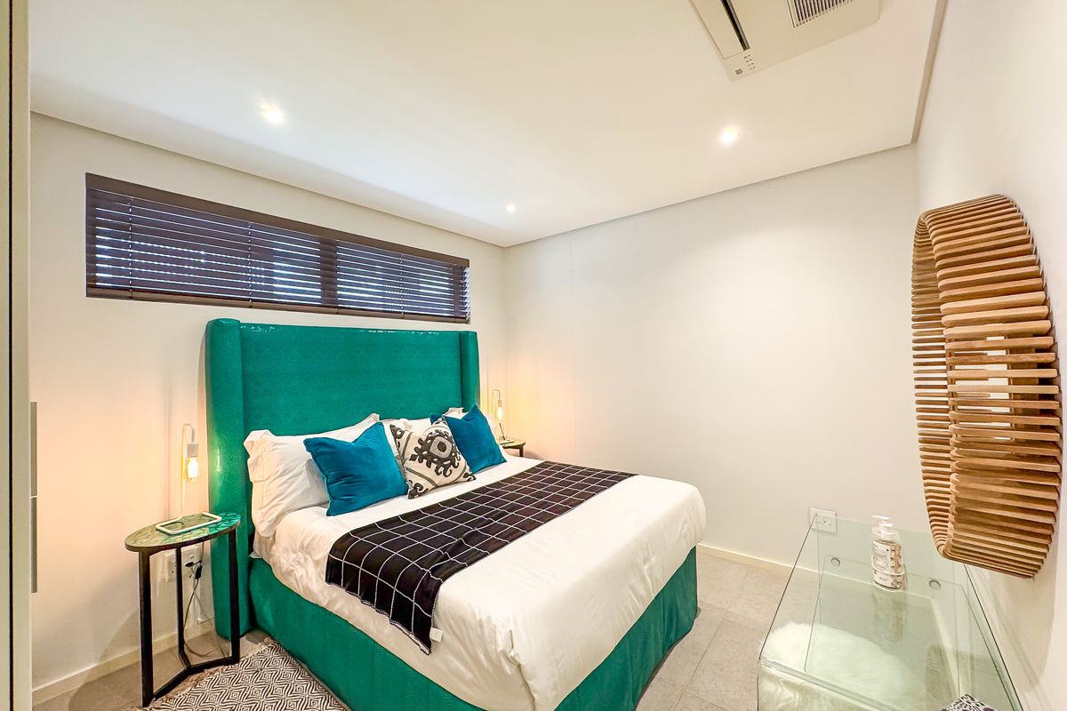 A modern, well-maintained bedroom featuring tiled flooring, recessed lighting, and a built-in ducted air conditioning system.