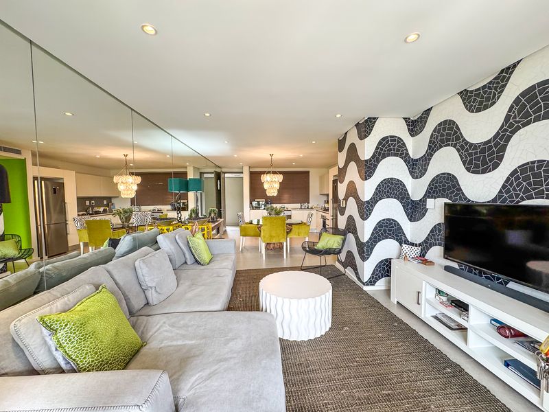 Spacious open-plan living and dining area featuring a mirrored wall, recessed lighting, and a distinctive patterned feature wall.