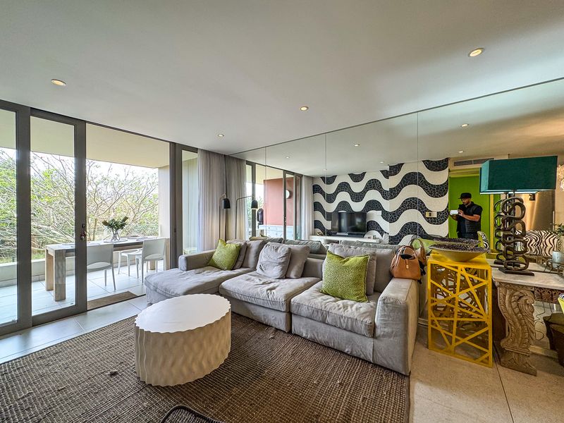 Spacious living room featuring large sliding glass doors leading to a patio, recessed lighting, and a decorative mirrored wall.