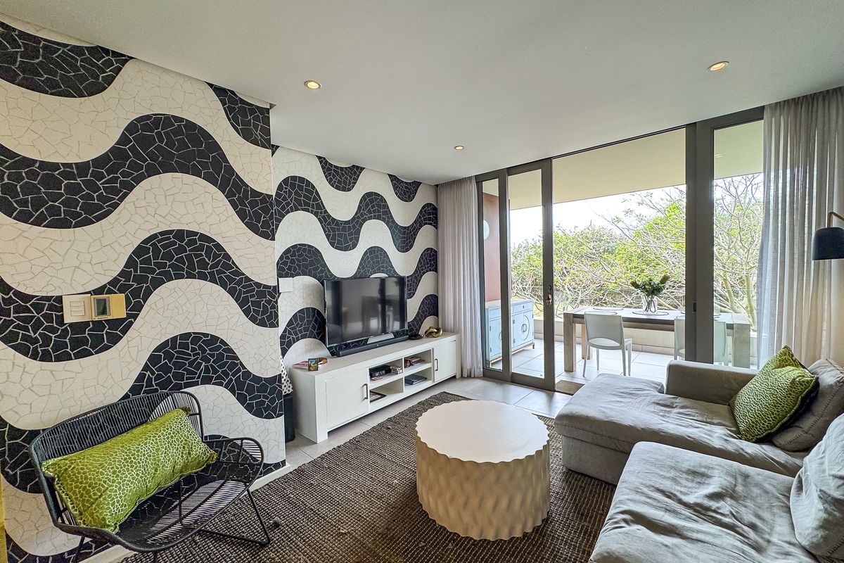 Modern living room featuring bold patterned wallpaper, recessed lighting, and large sliding glass doors that open onto a private balcony.