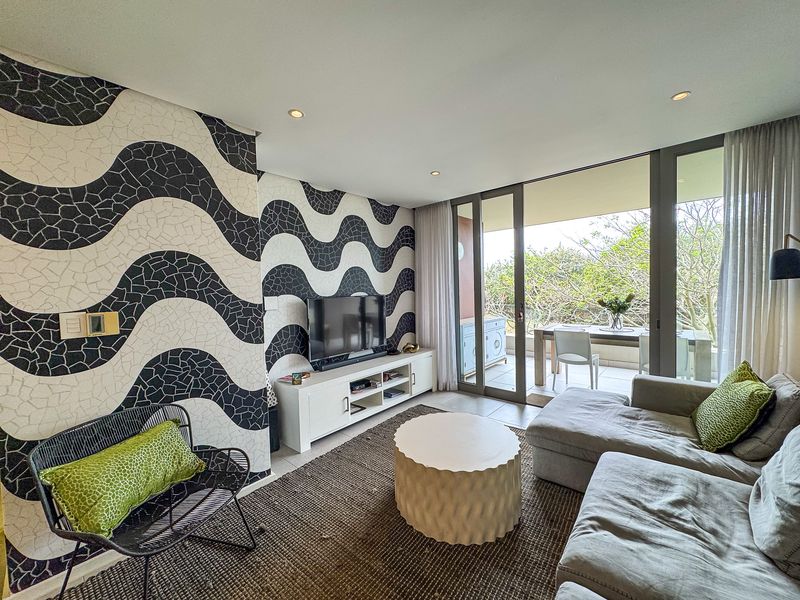 Modern living room featuring bold patterned wallpaper, recessed lighting, and large sliding glass doors that open onto a private balcony.