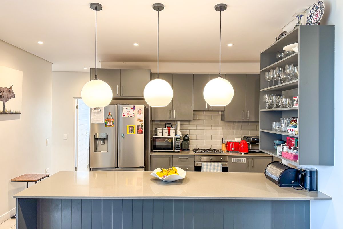 Modern kitchen featuring a central island with quartz countertops, grey cabinetry, subway tile backsplash, and integrated gas cooktop with oven.