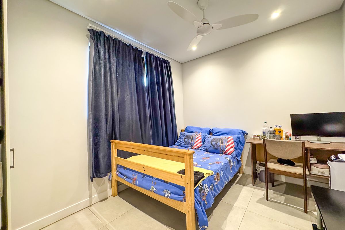 A well-maintained bedroom featuring neutral tiled flooring, recessed downlighting, a ceiling fan, and a built-in wardrobe.