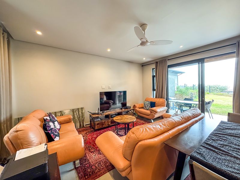 A comfortable living room featuring recessed lighting, a ceiling fan, and large sliding glass doors that provide direct access to the outdoor patio area.