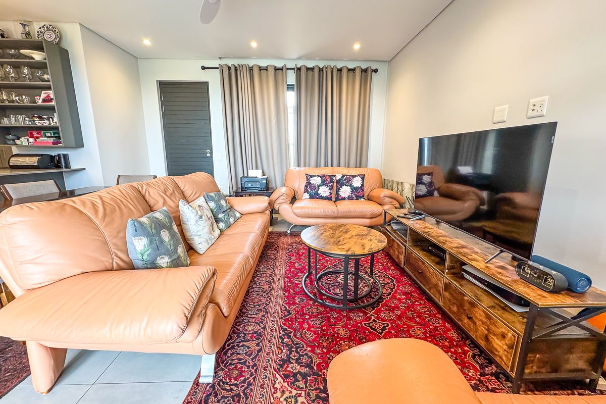 A well-maintained living room featuring tiled flooring, recessed downlighting, a ceiling fan, and a built-in shelving unit.