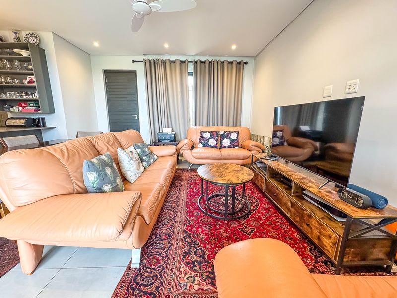 A well-maintained living room featuring tiled flooring, recessed downlighting, a ceiling fan, and a built-in shelving unit.