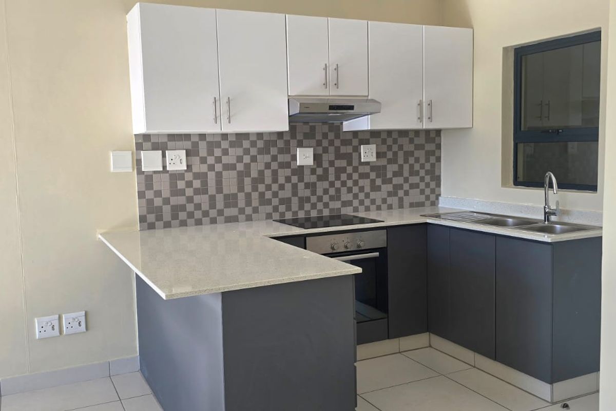 Modern kitchen featuring two-tone cabinetry, stone countertops, mosaic tile backsplash, and integrated appliances including an electric hob and oven.