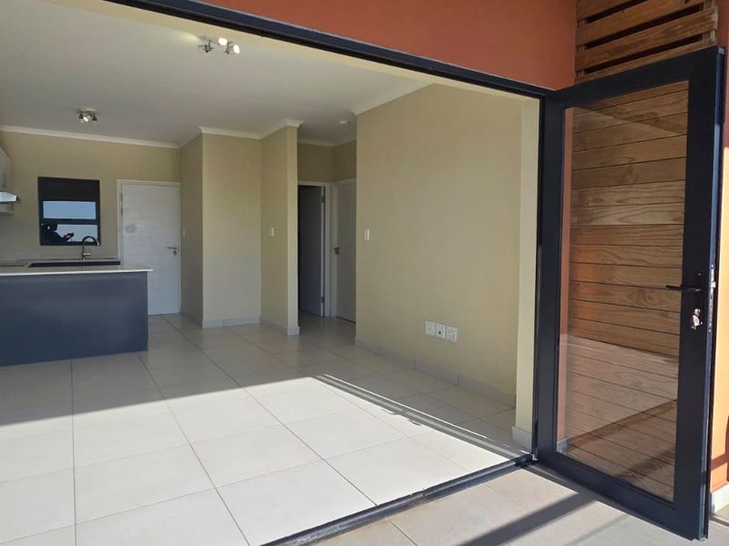 Open plan living area and kitchen featuring tiled floors, modern cabinetry, and large sliding doors leading to an outdoor space.