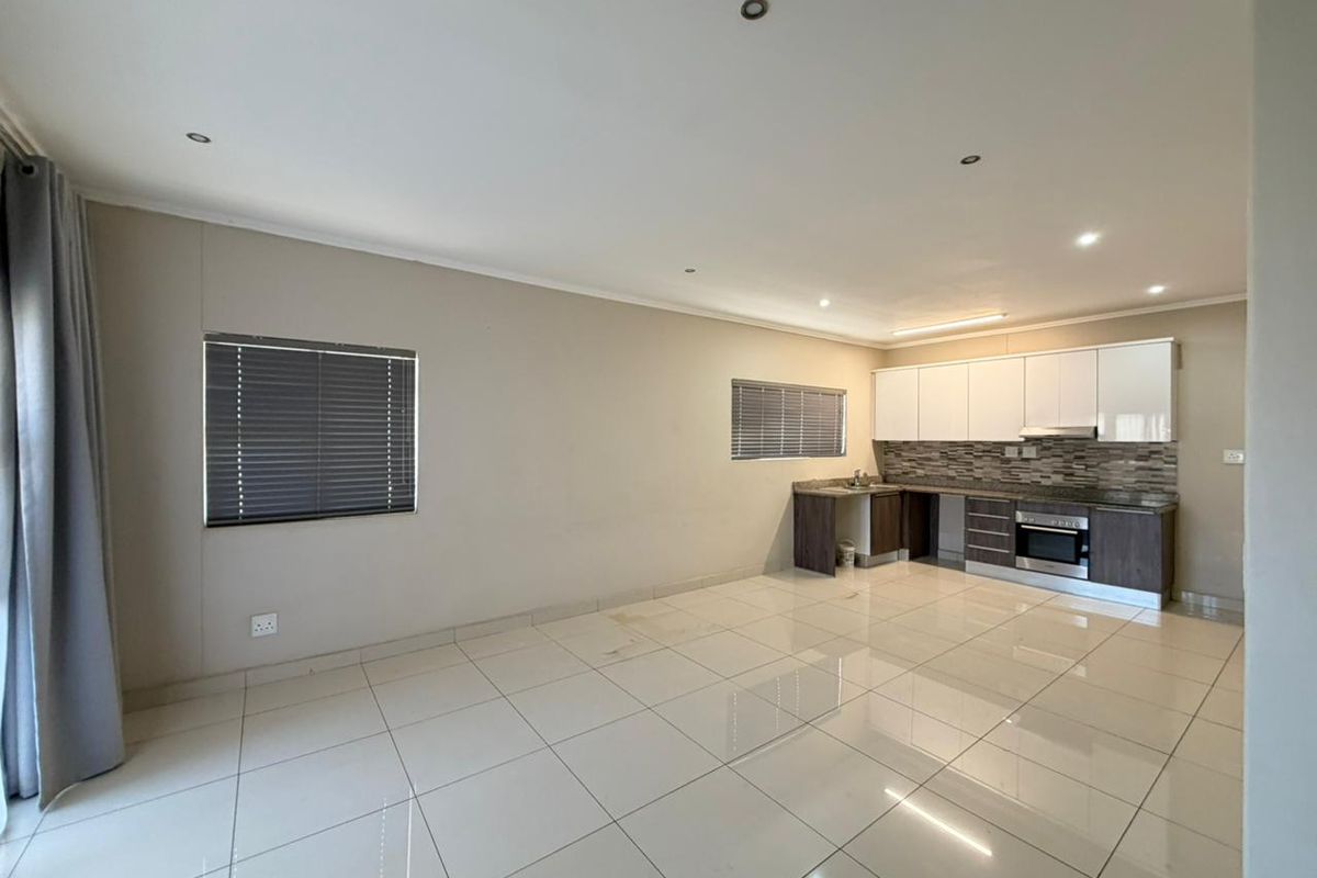 Open-plan living area featuring tiled floors, recessed lighting, and a functional kitchen with built-in cabinetry, granite countertops, and integrated oven.