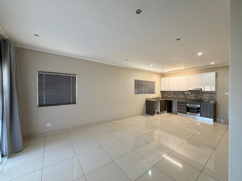 Open-plan living area featuring tiled floors, recessed lighting, and a functional kitchen with built-in cabinetry, granite countertops, and integrated oven.