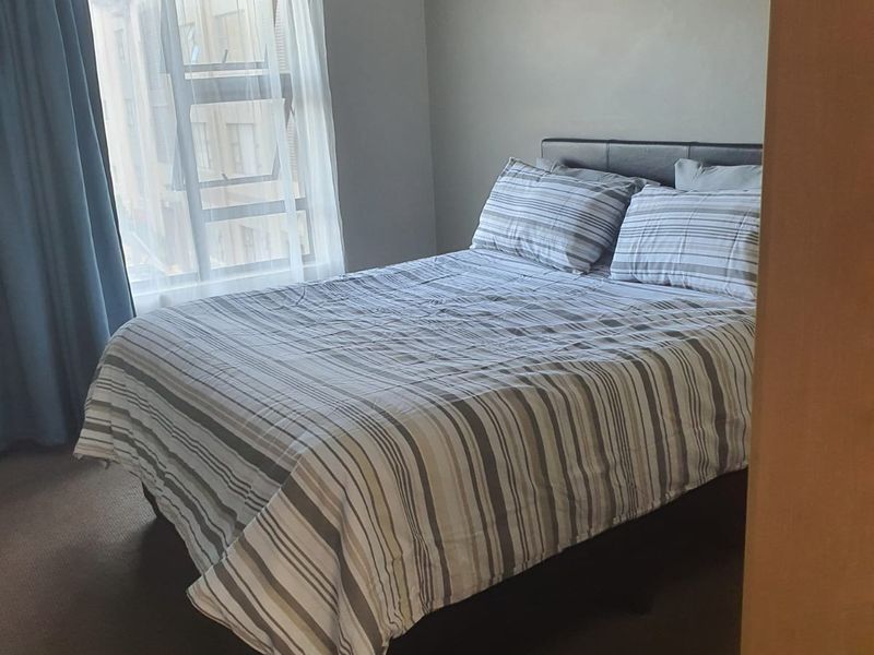 A standard bedroom featuring carpeted flooring and a window with natural light.