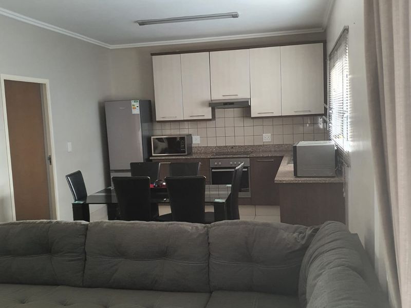 Open-plan living and kitchen area featuring built-in cabinetry, granite countertops, integrated appliances, and a wall-mounted air conditioning unit.