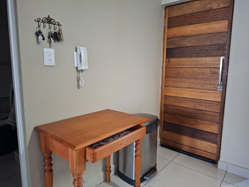 A functional entryway featuring a solid timber front door, tiled flooring, and a wall-mounted intercom system.