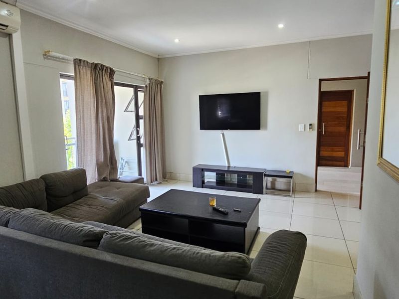 A living room featuring tiled flooring, recessed lighting, and a sliding glass door leading to an outdoor area.