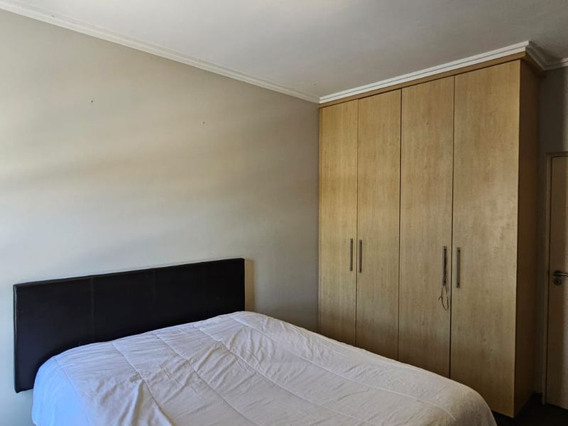 A bedroom featuring neutral walls, coving, and light wood-finish built-in cupboards providing ample storage space.