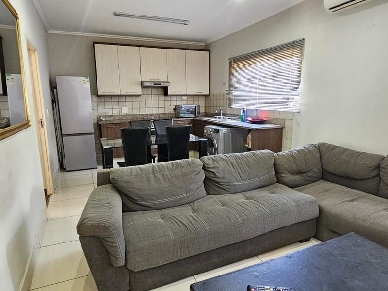 Open-plan living area featuring a functional kitchen with built-in cabinetry, tiled flooring, and an integrated air conditioning unit.