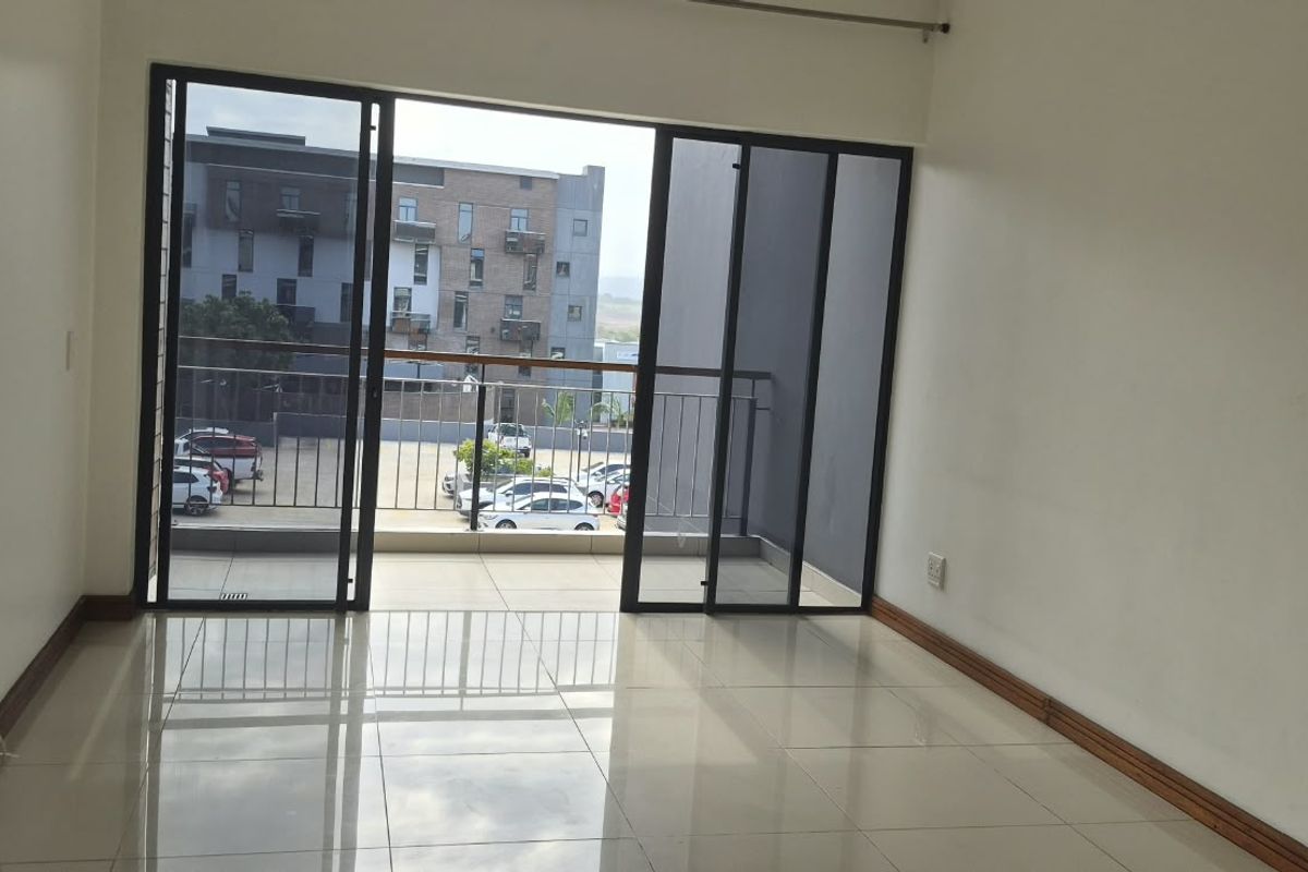 An open-plan living area featuring tiled floors and large sliding glass doors that open onto a private balcony with neighborhood views.