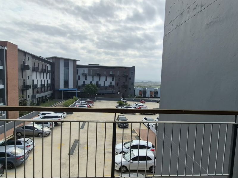 A balcony view overlooking the apartment complex parking area and surrounding buildings.