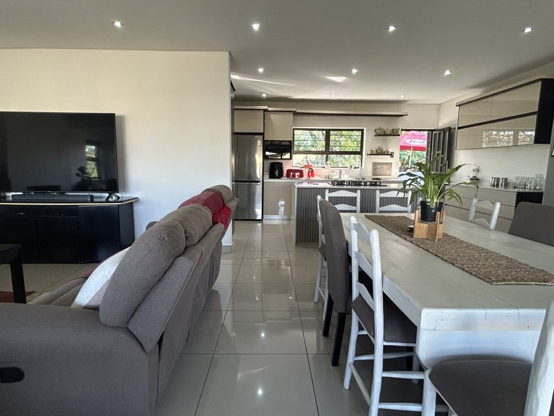 Spacious open-plan living, dining, and kitchen area featuring modern cabinetry, a central island, and polished porcelain floor tiles throughout.