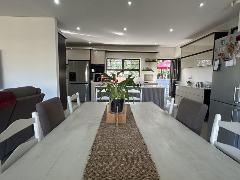 Spacious open-plan living and dining area featuring a modern kitchen with built-in cabinetry, a central island, and recessed lighting throughout.
