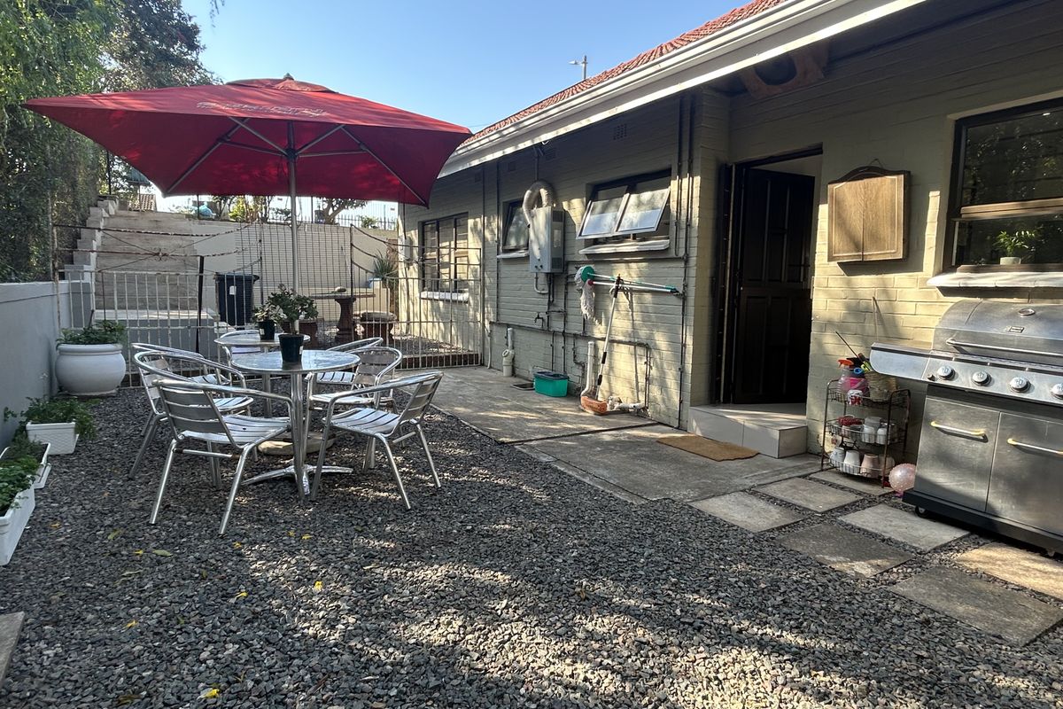 Rear exterior area featuring a brick facade, concrete paving, and gravel landscaping, providing a functional outdoor space for relaxation and entertaining.