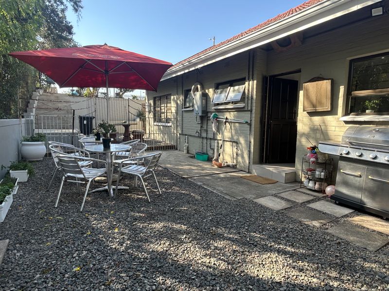 Rear exterior area featuring a brick facade, concrete paving, and gravel landscaping, providing a functional outdoor space for relaxation and entertaining.