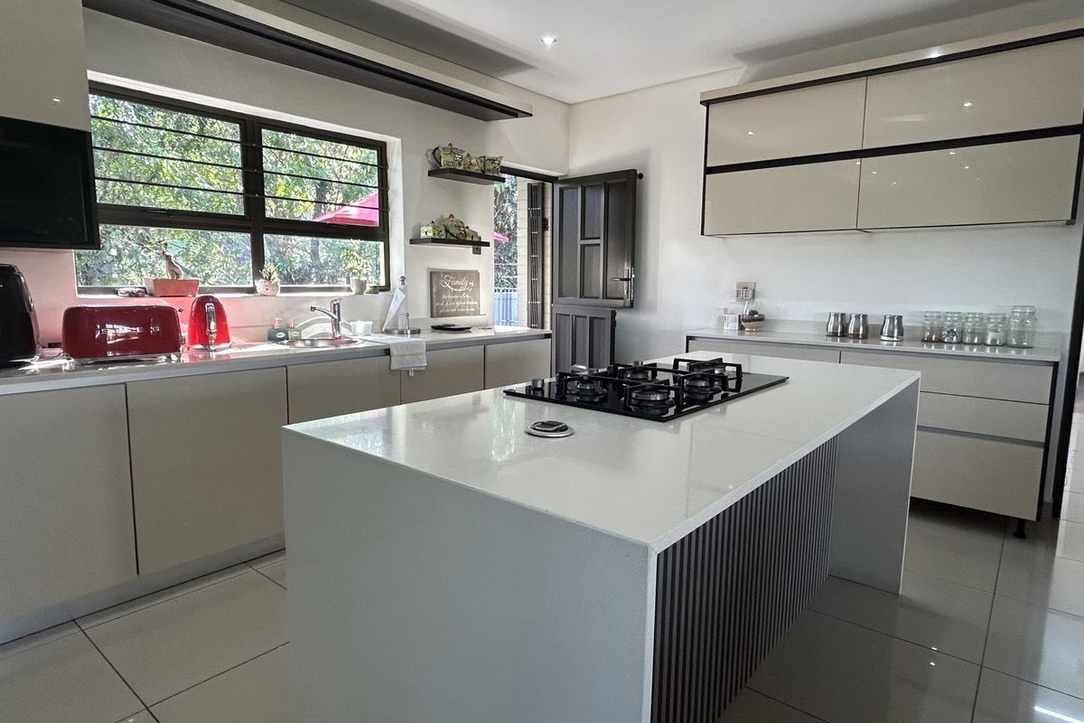 Modern kitchen featuring a central island with a gas cooktop, sleek cabinetry, tiled flooring, and ample natural light from the large window.