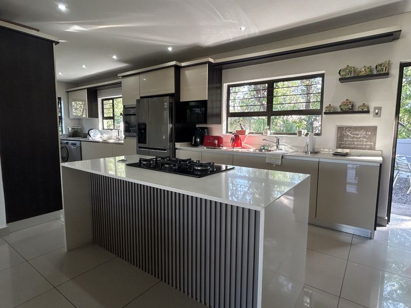 Modern kitchen featuring a central island with a gas hob, sleek cabinetry, stone countertops, and high-quality finishes throughout.
