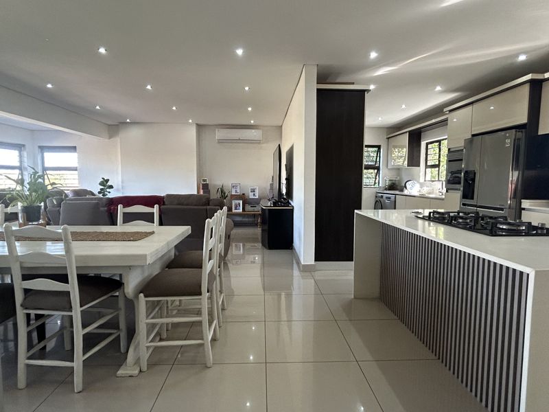 Spacious open-plan living area featuring a modern kitchen with a central island, gas cooktop, and sleek cabinetry, seamlessly flowing into the dining and lounge space.