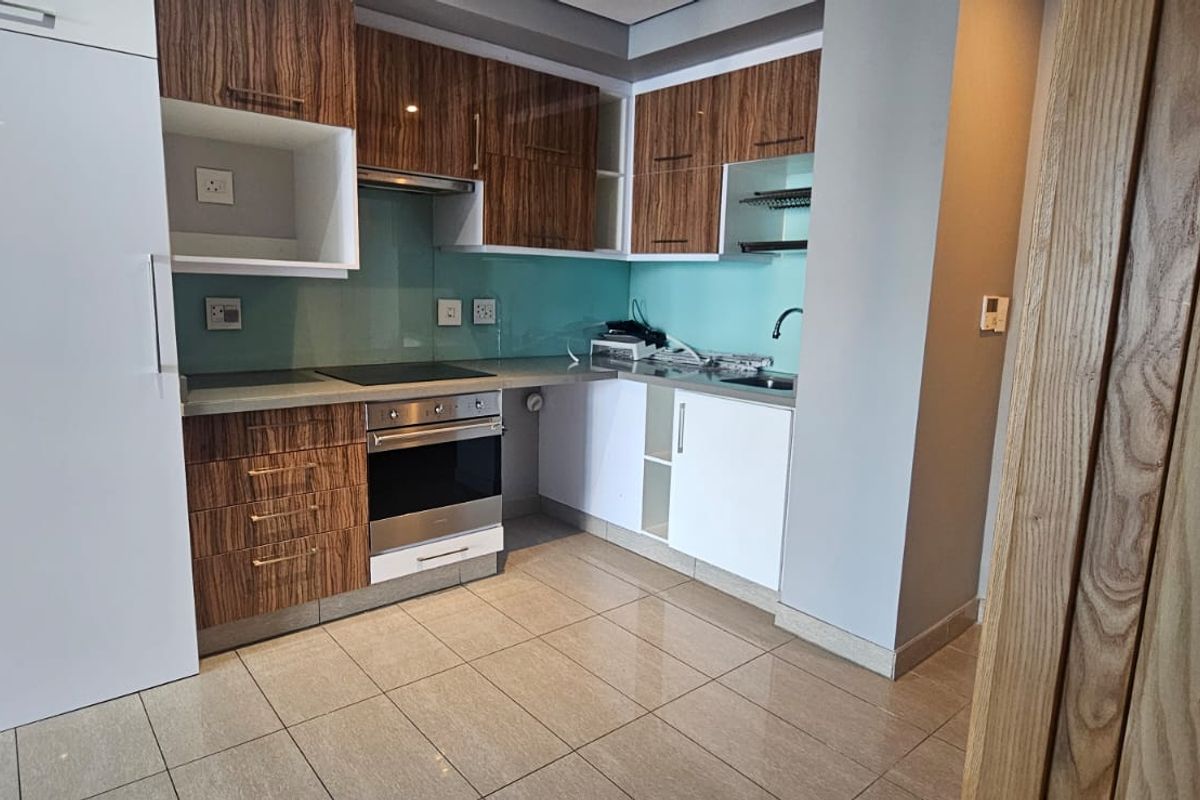 Modern kitchen featuring wood-grain and white cabinetry, integrated oven and hob, glass splashback, and tiled flooring in a clean, functional layout.