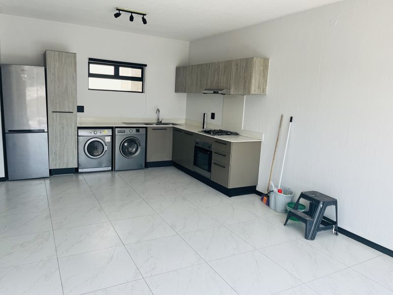 Modern kitchen featuring built-in cabinetry, gas hob, electric oven, extractor fan, and tiled flooring in an open-plan layout.