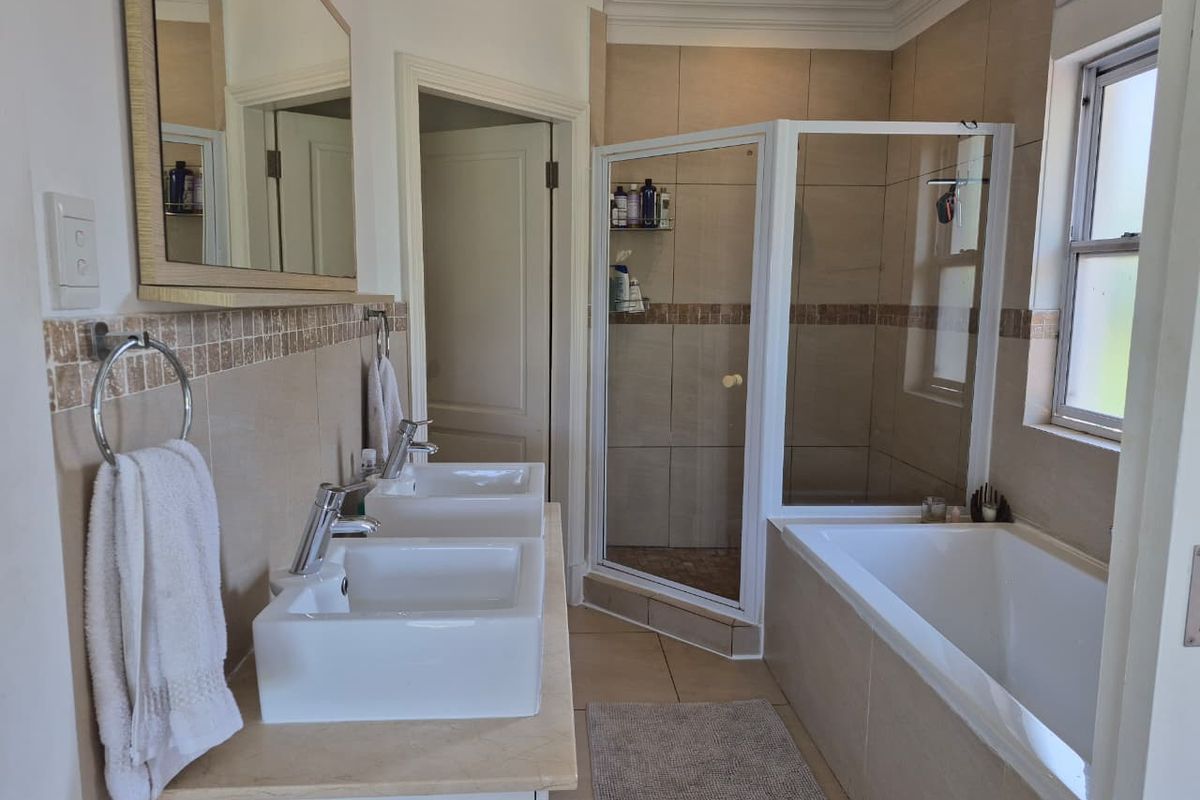 A well-maintained bathroom featuring a double vanity, a separate shower enclosure, and a built-in bathtub with neutral wall and floor tiling.