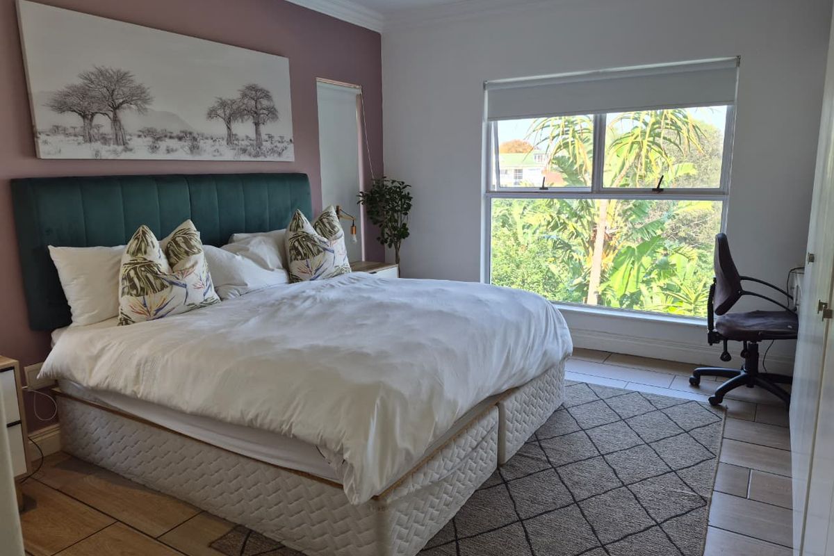 A well-lit bedroom featuring tiled flooring, recessed downlighting, and a large window with a roller blind, offering a bright and comfortable living space.