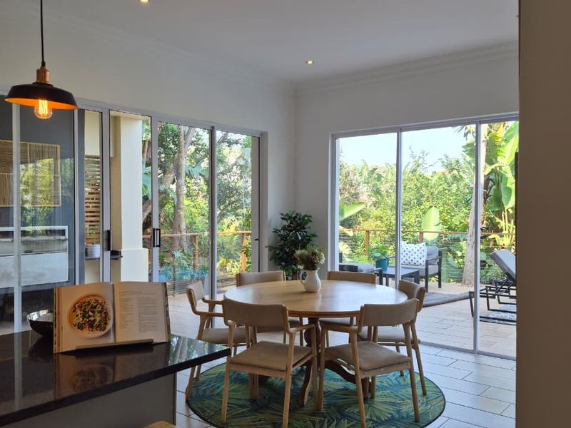 Open-plan living and dining area featuring modern tiled floors, recessed lighting, and large sliding glass doors providing seamless access to the outdoor patio.