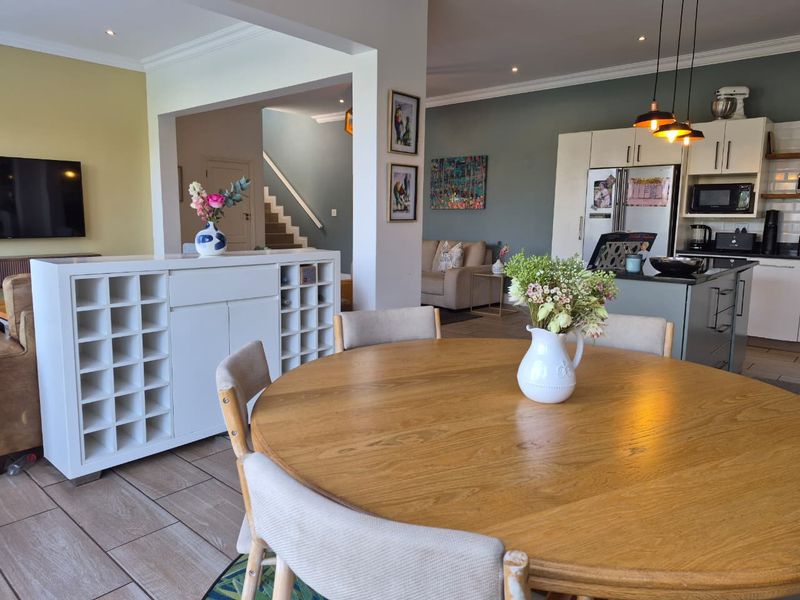 Spacious open-plan living area featuring a modern kitchen with island, tiled flooring, and a seamless flow into the dining and lounge spaces.