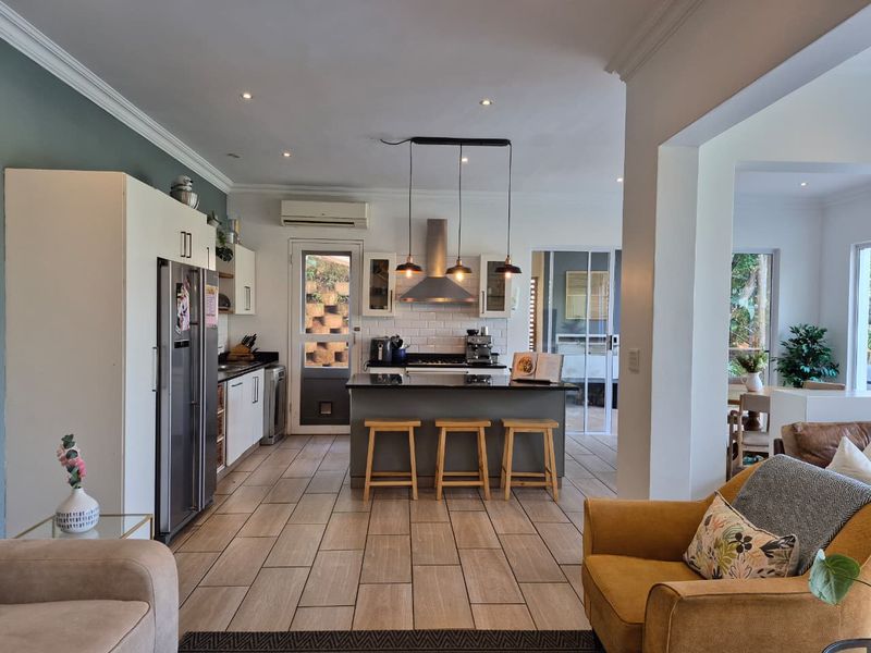 Spacious open-plan kitchen and living area featuring a central island, modern cabinetry, subway tile backsplash, and direct access to the outdoor patio.