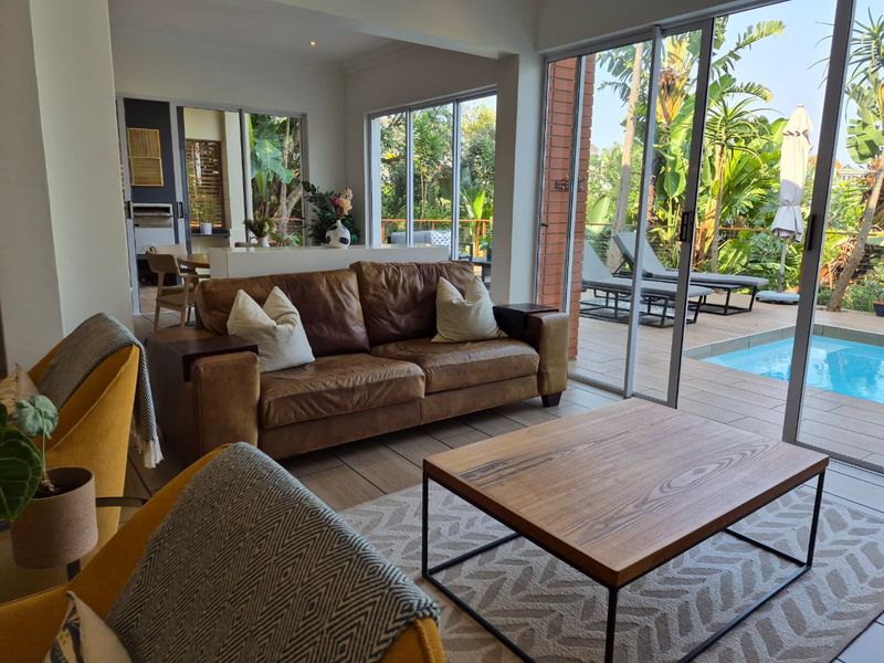 Bright open-plan living area featuring large sliding glass doors that provide seamless indoor-outdoor flow to the patio and swimming pool area.