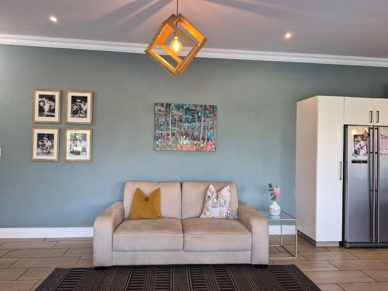 A well-maintained living room featuring neutral tiled flooring, crown molding, recessed lighting, and a built-in storage cabinet.