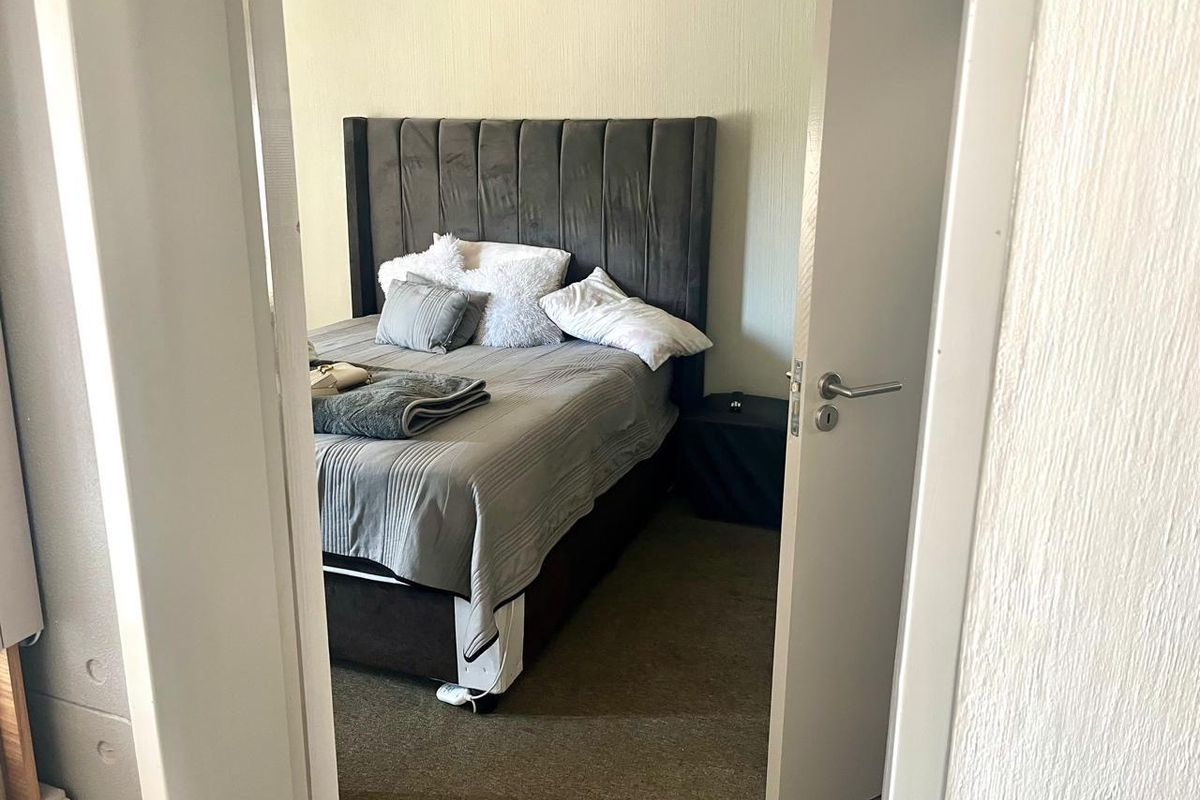 A view into a bedroom featuring carpeted flooring and a standard internal door, captured from the hallway.