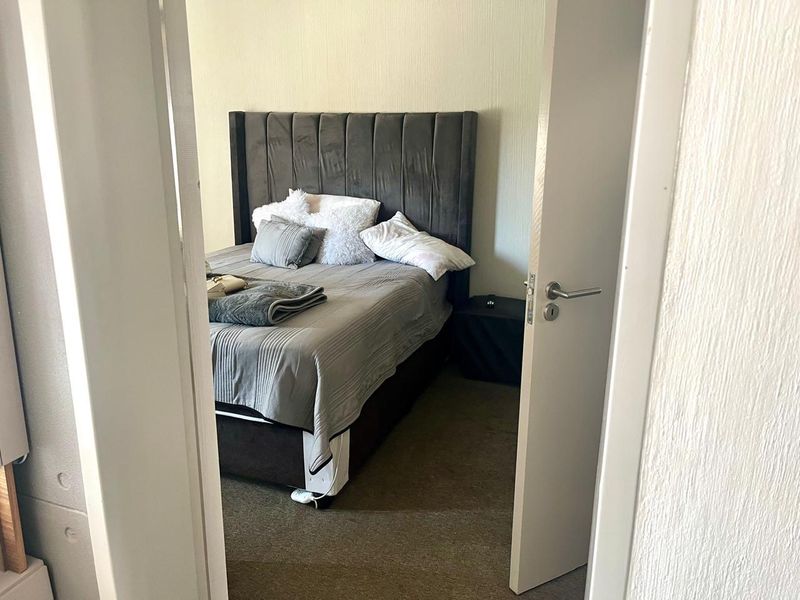 A view into a bedroom featuring carpeted flooring and a standard internal door, captured from the hallway.
