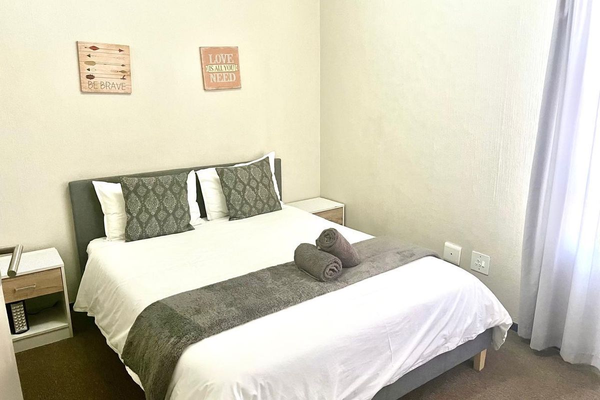 A well-maintained bedroom featuring neutral wall finishes, carpeted flooring, and integrated electrical points.